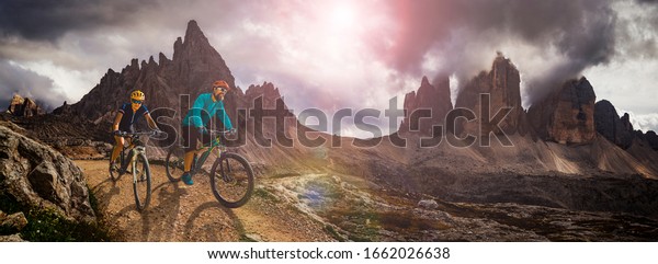 Cycling outdoor\
adventure in Dolomites. Cycling woman and man  on electric mountain\
bikes in Dolomites landscape. Couple cycling MTB enduro trail\
track. Outdoor sport\
activity.