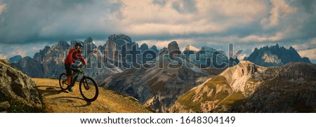 Cycling outdoor adventure. Man cycling on electric bike, rides mountain trail. Man riding on bike in Dolomites mountains landscape. Cycling e-mtb enduro trail track. Outdoor sport activity.