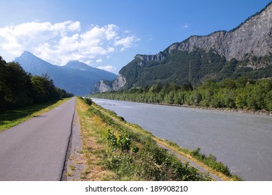 Cycling Path Along Rhine River In Switzerland. Mountain Landscape.