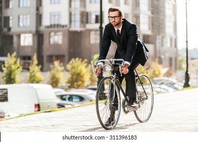 Cycling is the way to progress! Full length of handsome young businessman looking forward while riding on his bicycle  - Powered by Shutterstock