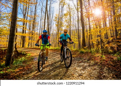 Cycling woman and man at Beskidy mountains autumn forest landscape. Couple riding MTB enduro track. Outdoor sport activity. - Shutterstock ID 1220911294