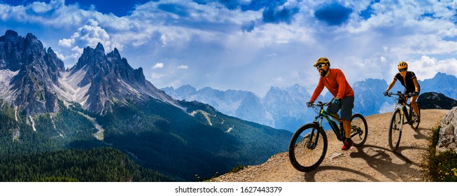 Cycling woman and man riding on bikes in Dolomites mountains andscape. Couple cycling MTB enduro trail track. Outdoor sport activity. - Shutterstock ID 1627443379