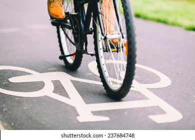 Cycling To Work. City Bike Sign On Asphalt Bikepath Man Cycling On Road, Colorful Vintage Light On Street, Commuting To Work On Bicycle In Urban Environment