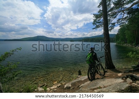 A cyclist admires the mountain lake Turgoyak, Ural, Russia.