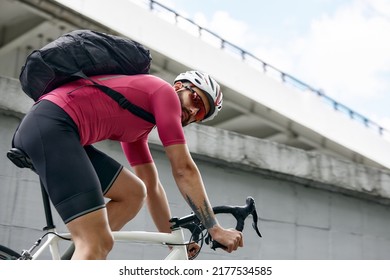 cyclist with a backpack while riding in the city on an exorbitant bike. Man in sportswear and a helmet rides the city square on a bike. Traveling around the city on a bicycle. - Shutterstock ID 2177534585