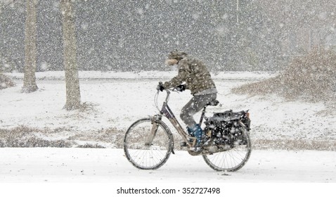 Cyclist Biking Through The Snow In Winter
