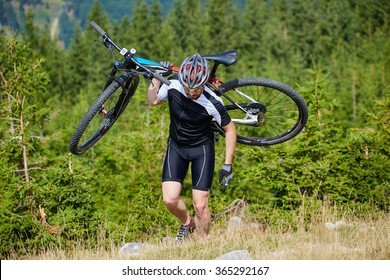 Cyclist Carrying His Mountain Bike On A Steep Uphill