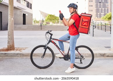 A cyclist delivery girl checks the address of her next shipment with her mobile phone