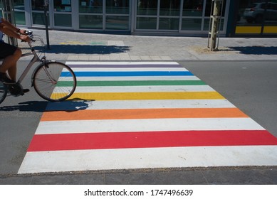 Cyclist Driving Over A Rainbow Zebra Crossing On A Sunny Day