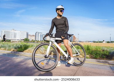 A Cyclist Enjoying a Sunny Day in the Park While Resting on a Bike Near a Modern City Skyline - Powered by Shutterstock