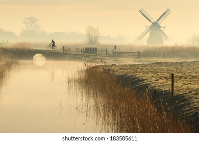 Cyclist and a foggy, spring sunrise in the Dutch countryside. - Powered by Shutterstock