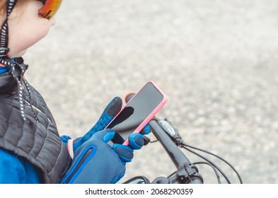 Cyclist hands in gloves hold a smartphone, mock up. Traveler looking for directions using maps in smartphone