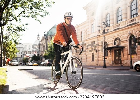 A cyclist in a helmet goes to work with a briefcase. Urban ecotransport.  Fitness watch on hand.