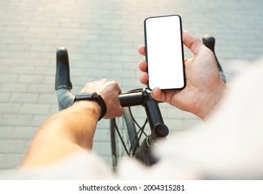 The cyclist is holding the mobile phone with blank white screen in one hand and bicycle in another one - Powered by Shutterstock