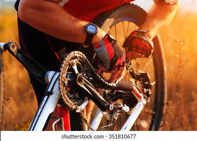 Cyclist man repairing his cycle in sunny meadow - Powered by Shutterstock