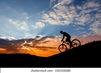 Cyclist man silhouette on mountain bike on the road.