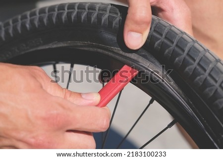 cyclist mechanic remove a tire of bicycle wheel by tire lever close up