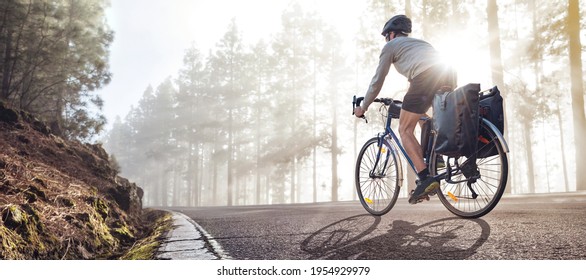 Cyclist on a bicycle with panniers riding along a foggy forest road - Powered by Shutterstock