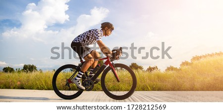 Cyclist pedaling on a racing bike outdoors in sun set .The image of cyclist in motion on the background in the evening.