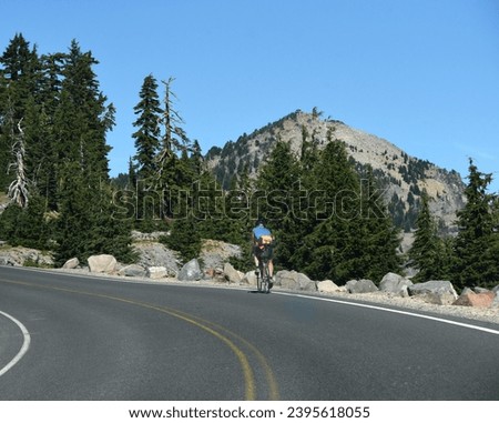 Cyclist pedals uphill on the Rim Drive, which circles Crater Lake, in Crater Lake National Park, Oregon.
