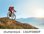 Cyclist in Red Jacket Riding the Bike in the Beautiful Mountains Down the Rock on the Sunrise Sky Background. Extreme Sport and Enduro Biking Concept.