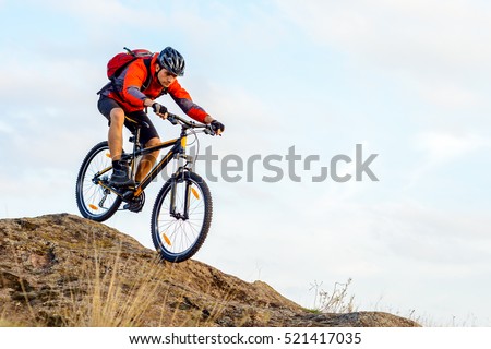 Cyclist in Red Jacket Riding the Bike Down Rocky Hill. Extreme Sport Concept.