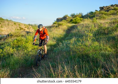 Cyclist In Red Jacket Riding The Mountain Bike On The Beautiful Spring Trail. Travel And Adventure Sport Concept