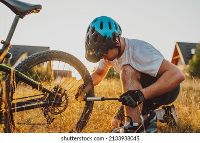 The cyclist repairs and changes the tire on his bike to the mountain at sunset. Bicycle tire repair. Selective focus. High-quality photo