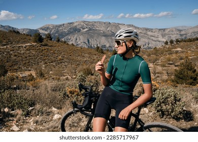 Cyclist is resting.Female cyclist is wearing cycling kit holding energy snack for endurance during bicycle training.Sport nutrition.Sport snack for cyclist.Granola energy bar. - Powered by Shutterstock