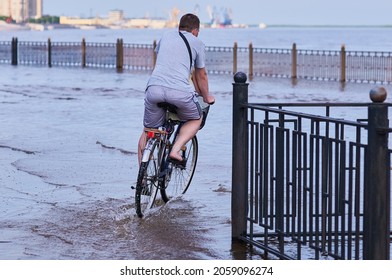 A cyclist rides along the flooded city embankment.Flood of the Amur River. Natural disaster. Blagoveshchensk, Far East, Russia.