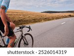 A cyclist rides down a scenic road with rolling hills in the background. The photo captures the sense of freedom and adventure associated with cycling.