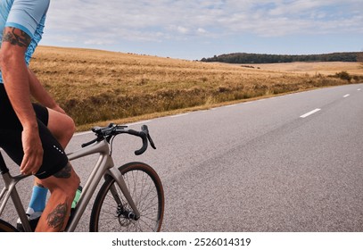 A cyclist rides down a scenic road with rolling hills in the background. The photo captures the sense of freedom and adventure associated with cycling. - Powered by Shutterstock