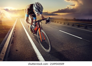 The cyclist rides on his bike at sunset. Dramatic background. - Shutterstock ID 2149543509