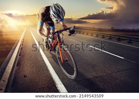 The cyclist rides on his bike at sunset. Dramatic background.