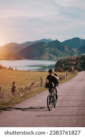 A cyclist riding a bike among the alpine mountains. Concept of the active healthy lifestyle. Mountain road with an alpine lake in the background. Vacation with nature. Concept of Human Recreation