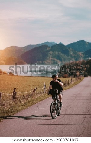 A cyclist riding a bike among the alpine mountains. Concept of the active healthy lifestyle. Mountain road with an alpine lake in the background. Vacation with nature. Concept of Human Recreation