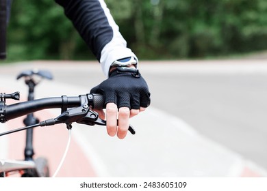 Cyclist riding bike on bicycle path. Close up of hand with smartwatch, fitness tracker and handlebar. Man doing sport and checks brakes. Ecological outdoor activity. Healthy, sustainable lifestyle - Powered by Shutterstock