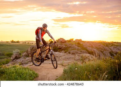 Cyclist Riding The Bike On The Mountain Rocky Trail At Sunset