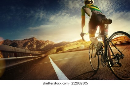 Cyclist riding a bike on an open road to the sunset 