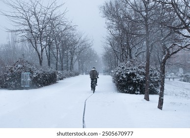 Cyclist riding on a snowy cycle path during a storm - Powered by Shutterstock