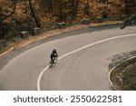 Cyclist riding a road bike on a scenic autumn road. Enjoy the vibrant colors and tranquility of nature. 