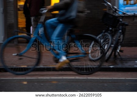 Cyclist riding swiftly along a modern urban pathway. Cyclist riding in cloudy Amsterdam in daytime. Motion blurred picture.