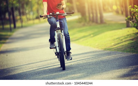 cyclist use cellphone while riding bike in tropical park - Powered by Shutterstock