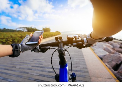Cyclist using smartphone for navigation when riding mountain bike on the sunrise coast