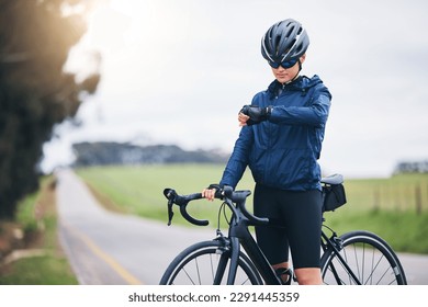 Cyclist woman, check time and nature on road for speed, gps and heart rate with fitness, health and wellness goal. Cycling, bicycle and female athlete with watch for exercise, training and workout - Powered by Shutterstock