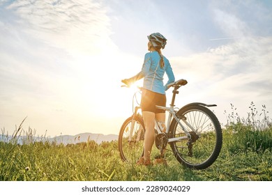 Cyclist Woman riding bike in helmets go in sports outdoors on sunny day a mountain in the forest. Silhouette female at sunset. Fresh air. Health care, authenticity, sense of balance and calmness. - Shutterstock ID 2289024029