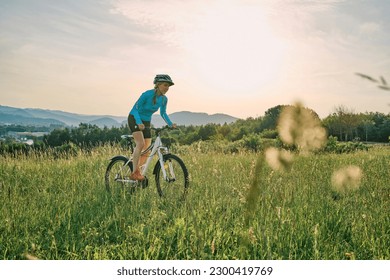 Cyclist Woman riding bike in helmets go in sports outdoors on sunny day a mountain in the forest. Silhouette female at sunset. Fresh air. Health care, authenticity, sense of balance. - Powered by Shutterstock