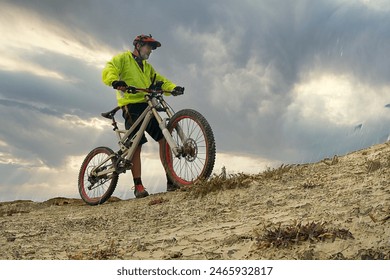 Cyclist with a yellow jacket and a red helmet riding a bicycle in the rain - Powered by Shutterstock