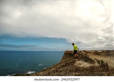 Cyclist with a yellow jacket and a red helmet riding a bicycle in the rain - Powered by Shutterstock