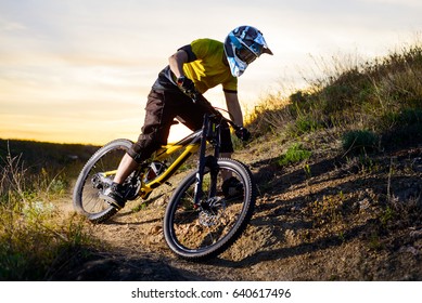 Cyclist In Yellow T-shirt And Helmet Riding The Mountain Bike Down Rocky Hill. Extreme Sport Concept.